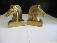 Pair of brass horse head bookends shown from the front, with both facing opposite directions.
