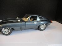 Side view of black Jaguar E-Type diecast model showing sleek body and wire-spoke wheels.