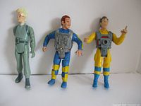 Three Ghostbusters figures displayed standing against white background, showing different character uniforms and gear