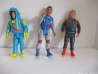 Photo of three Ghostbusters action figures showing different style outfits and colors.