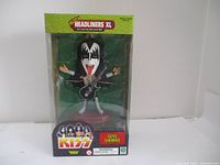 Front clear view showing Gene Simmons figurine in box with guitar and makeup visible, packaging intact.