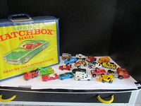 Full lot with matchbox collector's case and 16 assorted Matchbox cars arranged on a white surface, case is yellow with green car image.