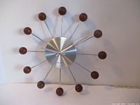 Full view of the Verichron wall clock showing its unique mid-century modern design with wooden ball hour markers and radiating metal spokes.