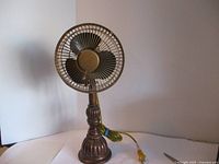 Front view of vintage metal table fan showing decorative base, metal cage, and black blades.