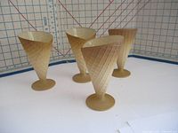 Four amber-colored vintage sundae glasses with waffle cone texture, standing upright on a white grid background showing their shape and textured detail.