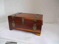 Front view of vintage wooden box showing metal latch and hinges on lid