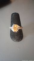 Front view of oval citrine ring on black display stand showing gemstone and band details.