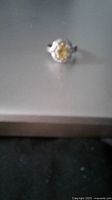 Blurry photo of the ring on a flat surface showing the oval citrine and diamonds surrounding it.
