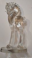 Front and side views of clear art glass pony sculpture showing overall shape, details of mane, legs, and base.