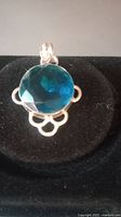 Front close-up of blue topaz pendant showing faceted stone and silver setting with decorative loops