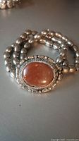Close-up of sterling silver bracelet showing jasper stone centerpiece and triple strand silver bead band.