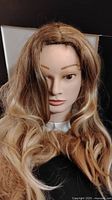 Front view of the long wig on a mannequin head showing blonde and brown highlights with wavy texture.