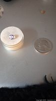 Photo of a single round loose amethyst gemstone next to a US quarter for size reference.
