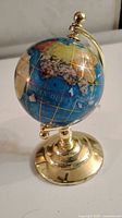 Photo showcasing the Lapis Lazuli gemstone globe on its gold tone stand with detailed map and gold grid lines.