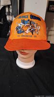 Front view of the bright orange baseball cap featuring 'THE ORANGE CRUSH' text and football player graphic with 'GO BRONCOS GO' text beneath.