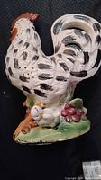 Photo showing the large vintage glazed ceramic chicken figurine with black spots and two chicks on a green base.