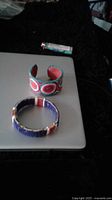 Photo showing two bracelets on a grey surface: one Native American beaded bracelet and one vintage Indian cuff bracelet with colorful circular designs.