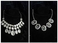 Two vintage statement necklaces displayed on black bust: one with multiple oval clear stones, one with five large oval stones surrounded by rhinestones.