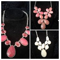 Photo showing three vintage statement necklaces displayed on black velvet stands. Left: pink large oval and teardrop stones necklace on curb chain. Top right: pink floral stones necklace. Bottom right: white geometric cluster stone necklace.