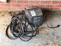 Full view of the Craftsman air compressor including power cord and hoses, placed on a garage floor with brick wall background.