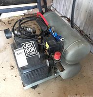 Oblique view showing cast iron cylinder housing, pressure regulator knob, attached hoses and blow gun