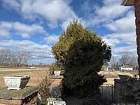 Three square concrete planters placed outdoors near a brick house wall, visible weathering and moss on surfaces.