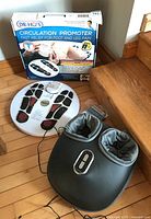 Dr. Ho Circulation Promoter original box, device, and Nekteck foot massager and warmer on floor near stairs.