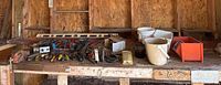 Wide view of garage shelf holding various tools and items including screwdriver set, clamps, and buckets
