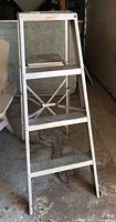 Front view of used aluminum step ladder showing three steps and top platform