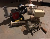 Group image of four meat grinders including electric and manual types with accessories, showing overall lot contents