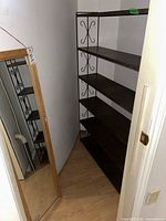 Metal shelf unit with dark wood shelves and decorative metal sides, placed in a corner.