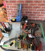 Overview of assorted tools including screwdrivers, pliers, scissors, hammer, measuring tape, portable light, spool of string, and toolbox.