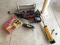 Entire lot arranged on floor showing all items including bungee system, pole saw, charger, pump, and work light