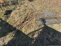 Photo showing the two metal live animal traps and several pieces of rusted rebar on outdoor grass.