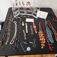 Wide shot of assorted jewelry laid on black cloth, showing necklaces, bracelets, earrings, and watches.
