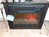 Front view of the electric floor model fireplace showing the black frame and glowing log display.