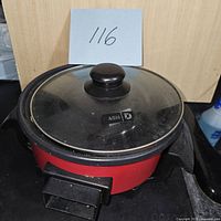 Front view of the red electric fryer with glass lid and black knob on top showing light use marks.