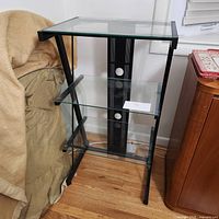 Full view of the metal and glass display shelves placed on wooden floor beside furniture.