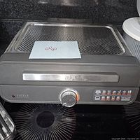 Front view of Ninja Sizzle indoor grill showing control knob, brand name, and perforated grill plate in place.