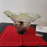 Side angle view showing scalloped rim, green stripes, fish and sea motifs in the glass.