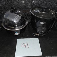 Dash mini rice cooker and egg cooker together on black surface with sticker labeled 91.