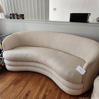 Curved kidney shape sofa in white fabric showing the front angle and floor placement.