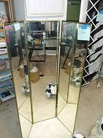 Front view of the three-panel mirror showing all panels reflected indoors with some items behind it.