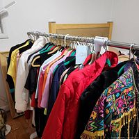 Clothing rack with assorted women's tops and jackets in various colors and styles, focusing on red and patterned jackets on the right end.