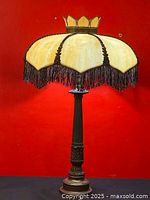 Full view of the antique slag glass table lamp with brass base against a red background showing height and overall design