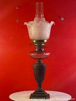 Full view of antique Victorian lamp with clear chimney, frosted floral glass shade, ruby cut glass double burner, and wooden base.