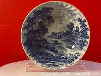 Top view of blue and white ironstone bowl showing the intricate pastoral scene transfer pattern with trees, houses, river, and boats.