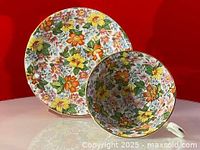 Teacup and saucer from Radfords with colorful chintz flowers pattern against red background.