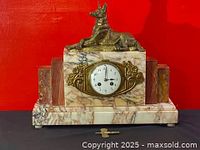 Full front view of marble clock case with bronze dog on top against red background