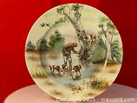 Full view of the Royal Bayreuth cabinet plate showing the hunting scene with hunter and two dogs near a tree and water.